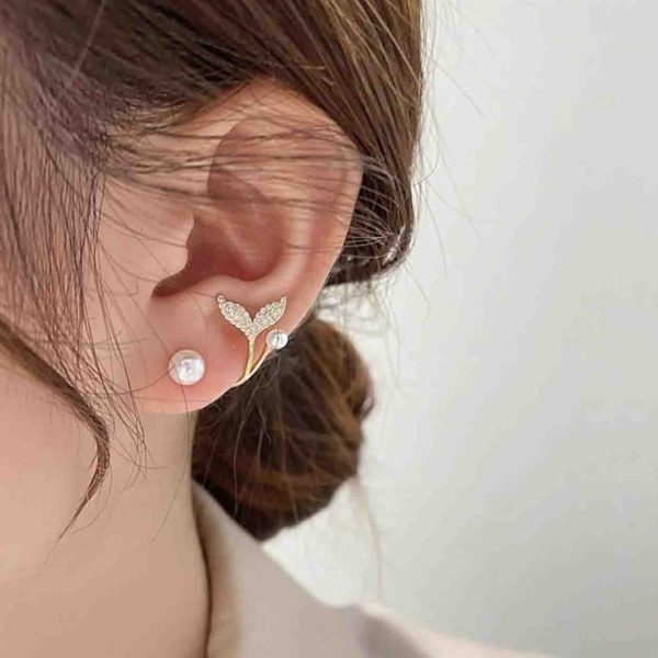A pair of artificial earrings with a pearl and a fish tail charm.