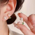 A pair of gold earrings with a flower design and a pearl in the center. Jewelry to Pakistan